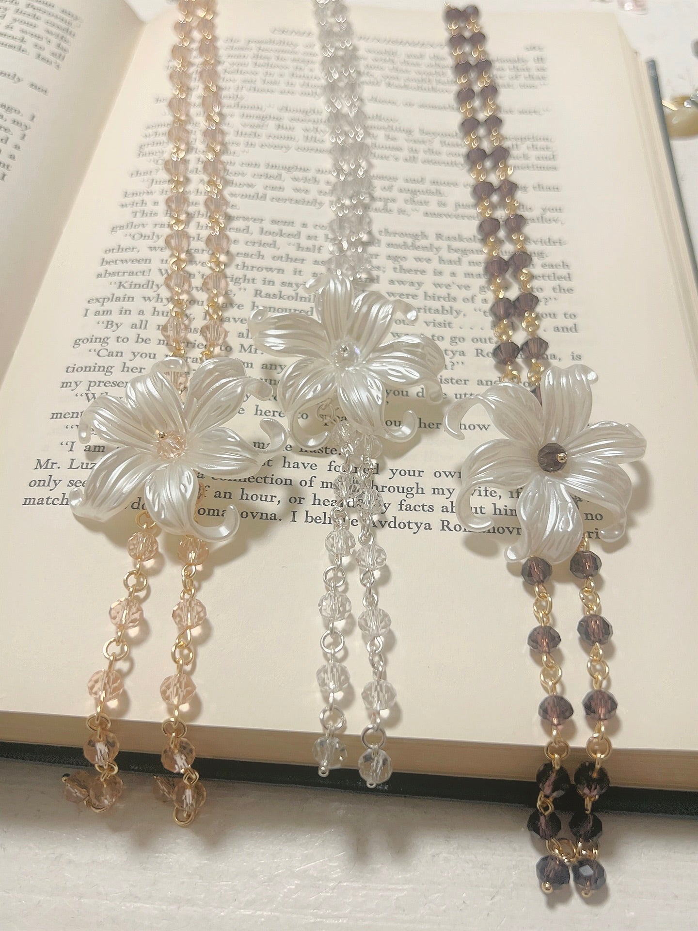 Elegant flower pendant necklaces with crystal beads, displayed on an open book.