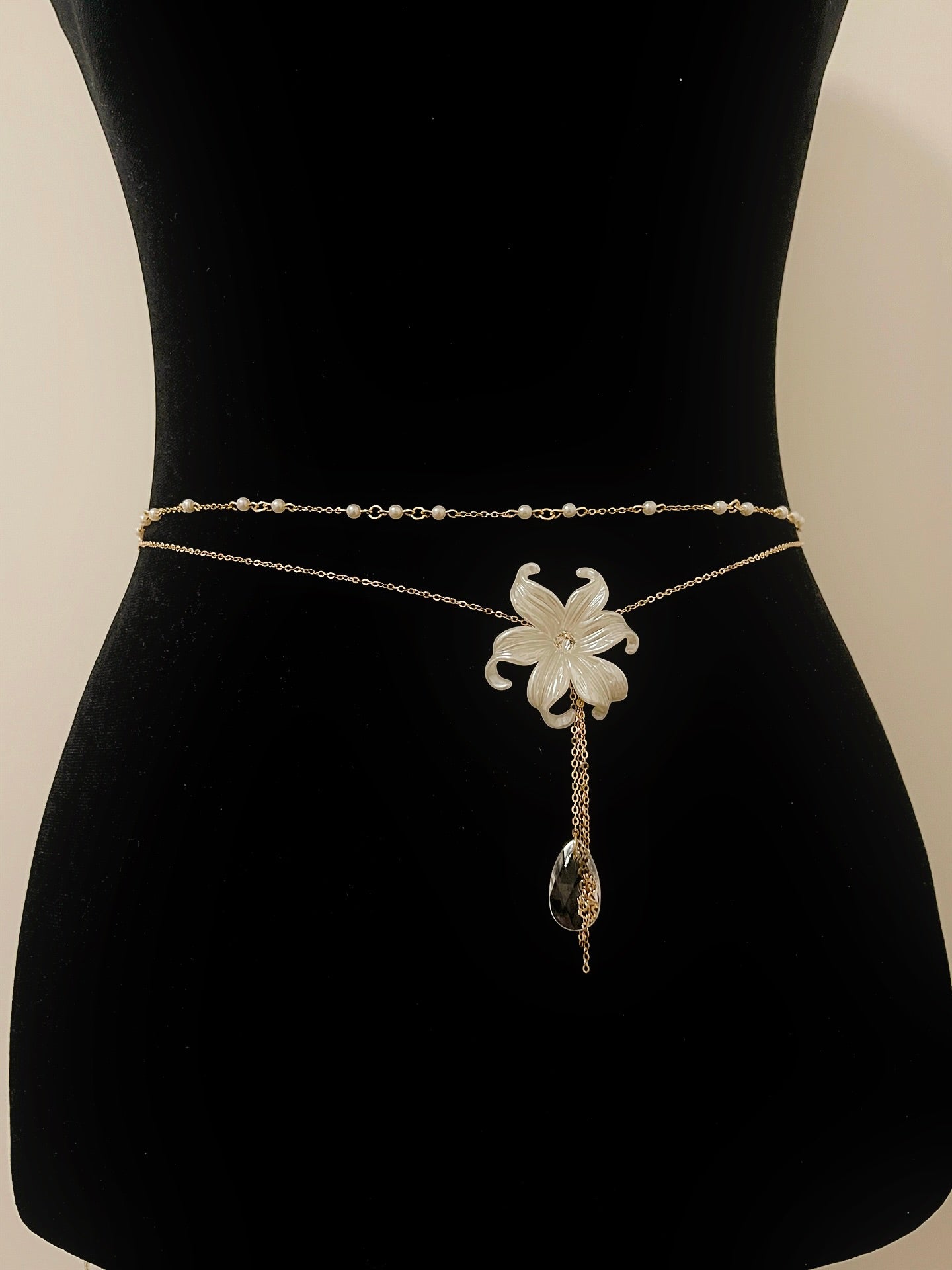 Elegant gold waist chain with white flower pendant and crystal drop, perfect for boho or bridal wear.