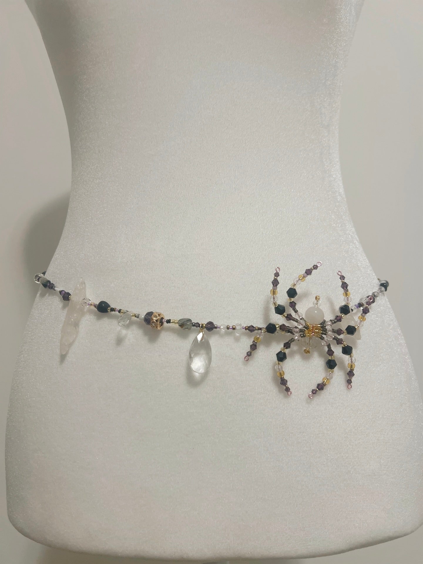 Handmade beaded waist chain with spider charm, crystal drops, and purple/gold beads on mannequin