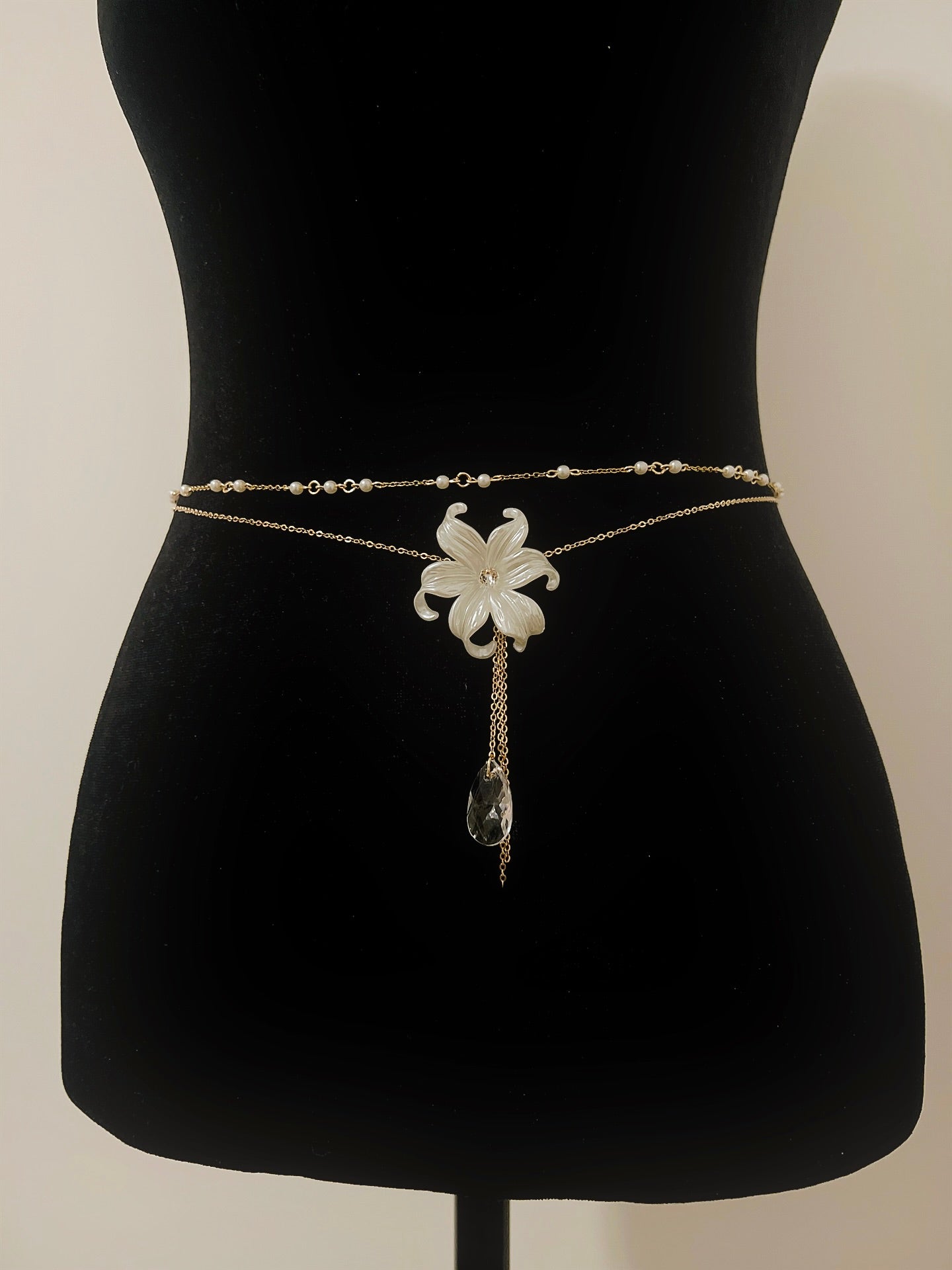 Delicate gold waist chain with white flower pendant and crystal drop, perfect for boho or bridal wear