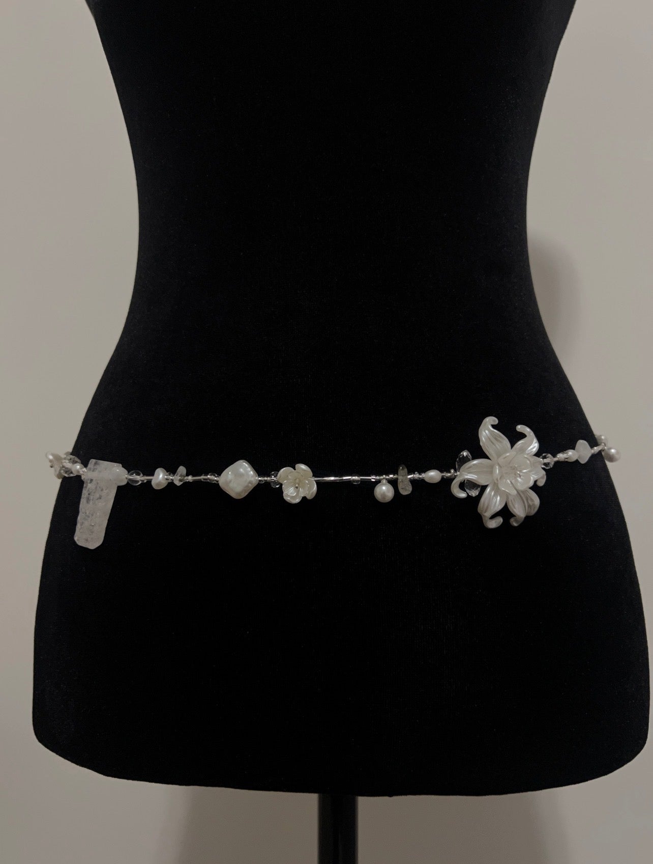 Elegant handmade waist bead with floral design and pearls, perfect for accessorizing any outfit.
