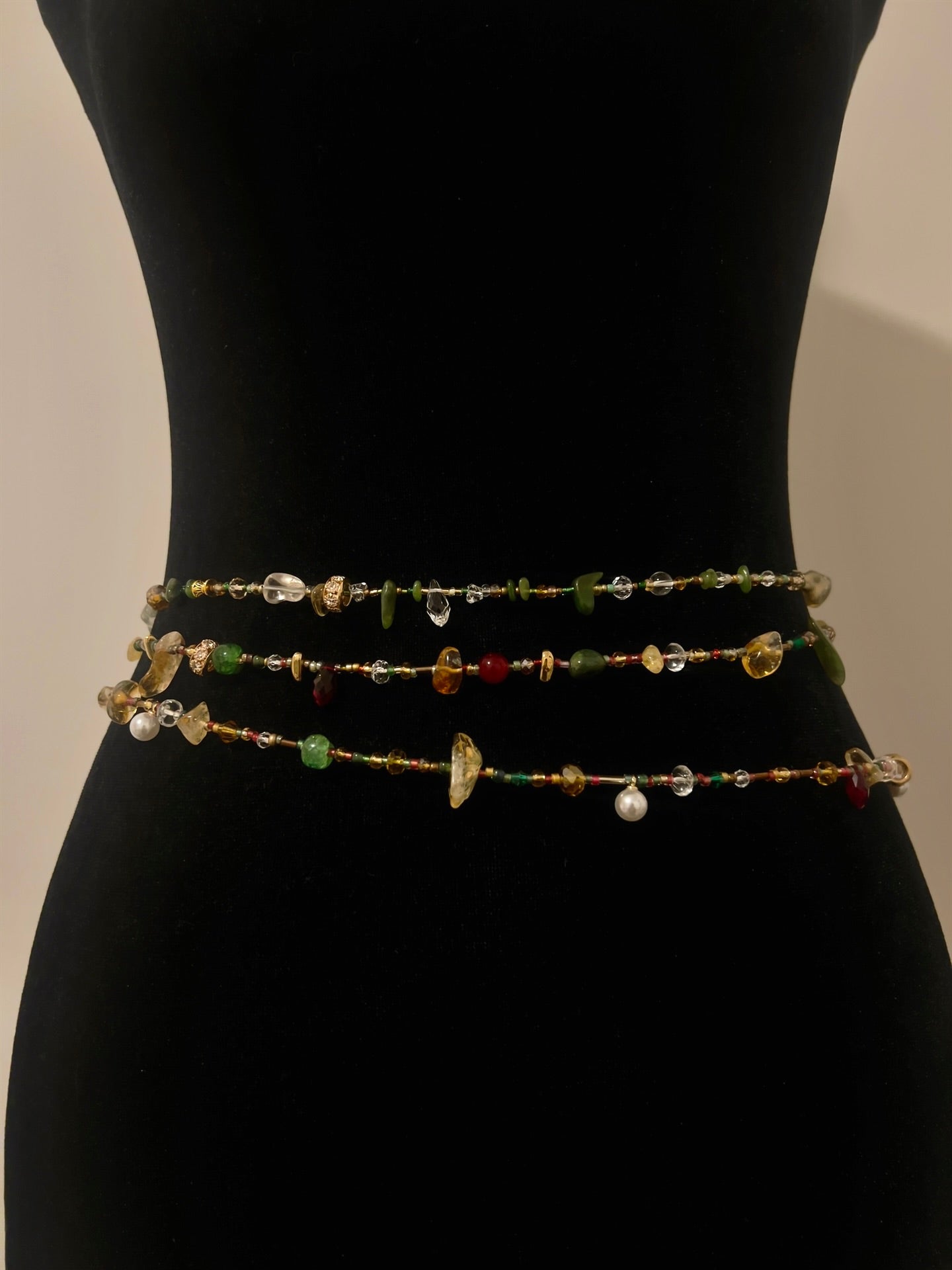 Handmade beaded waist chain with colorful gemstones and pearls, displayed on black mannequin