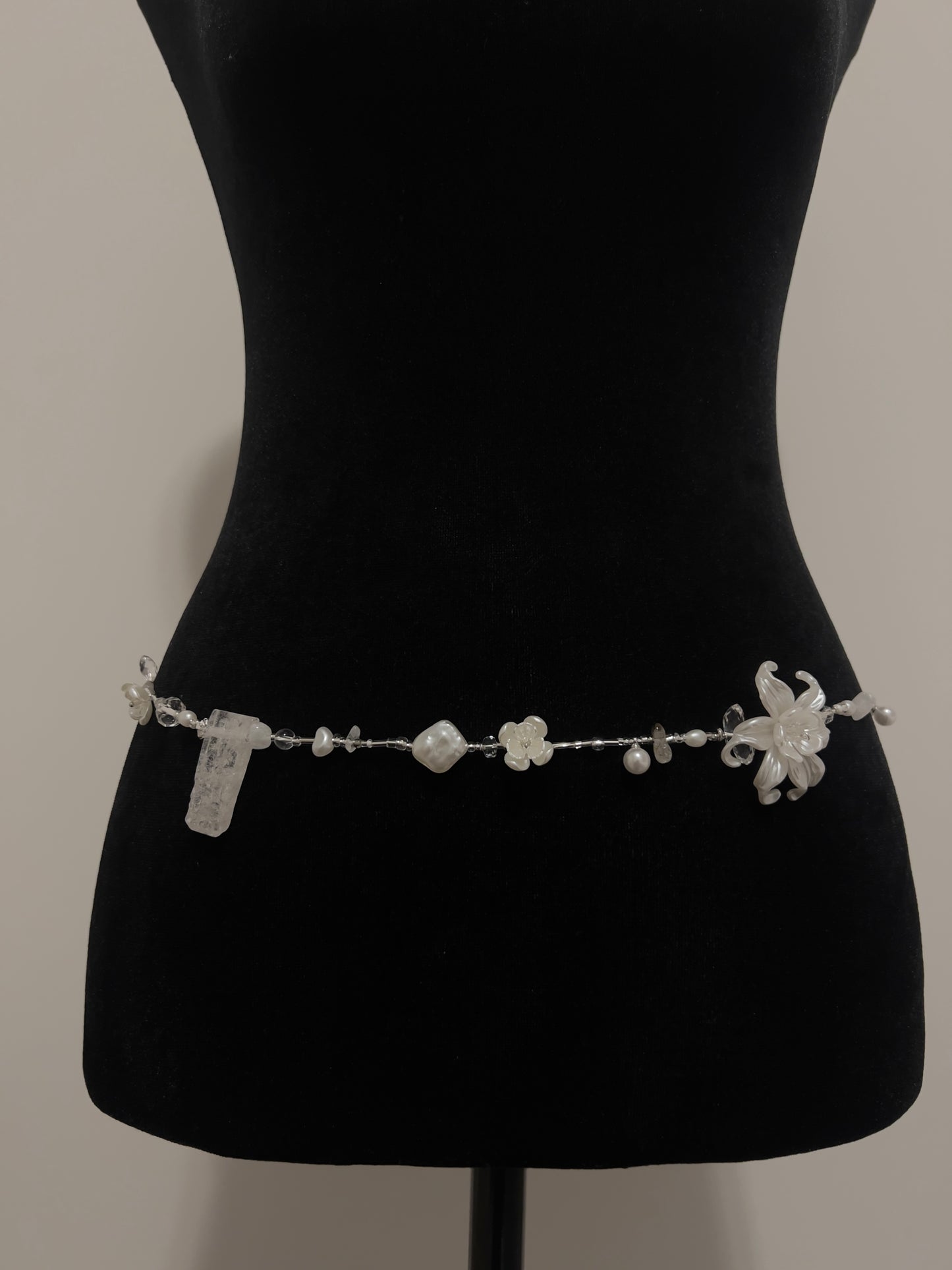 Elegant waist bead with pearls, crystals, and floral accents on black mannequin