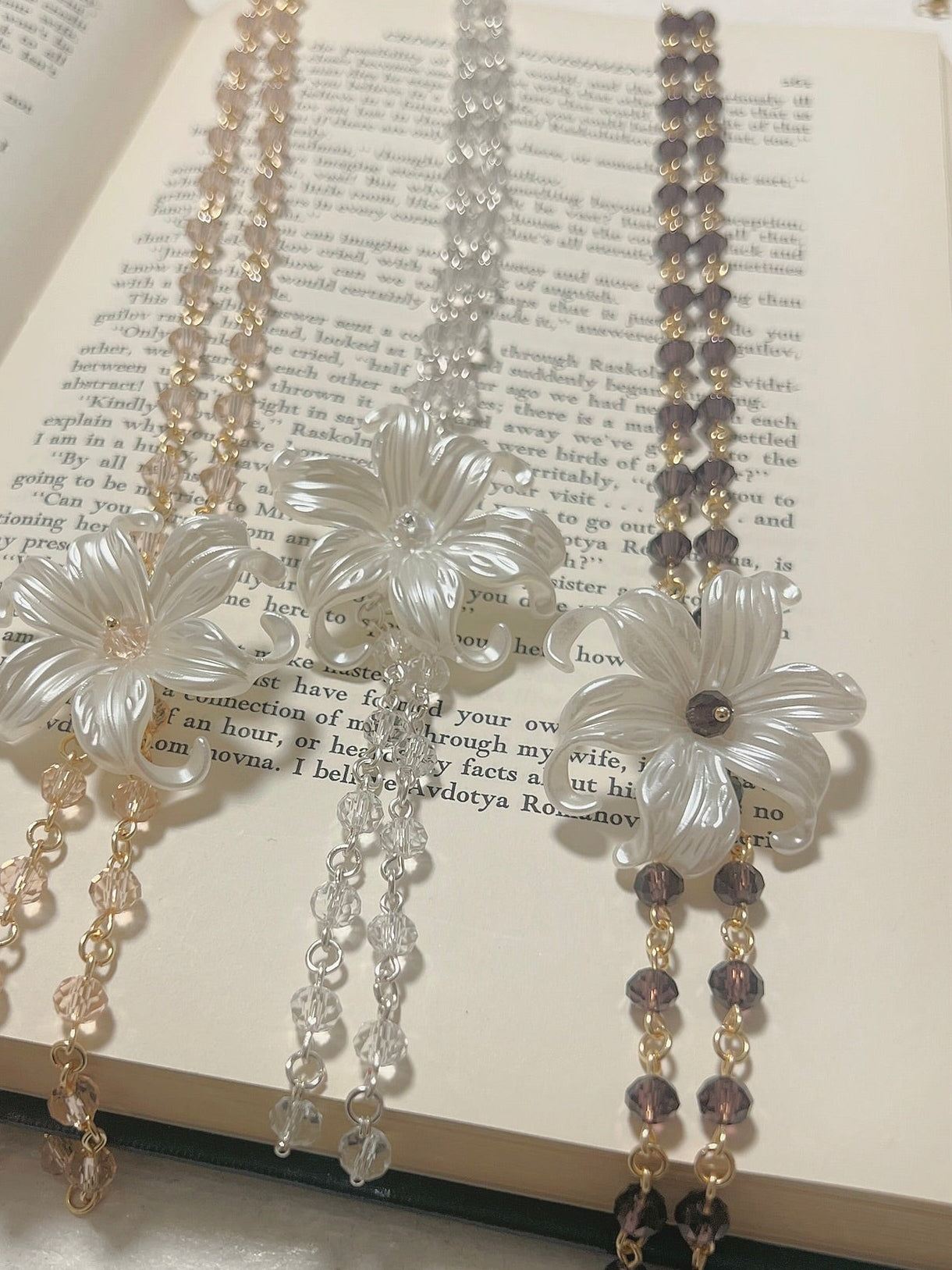 Elegant flower-shaped necklaces with crystal beads, displayed on an open book, perfect for handmade jewelry lovers.