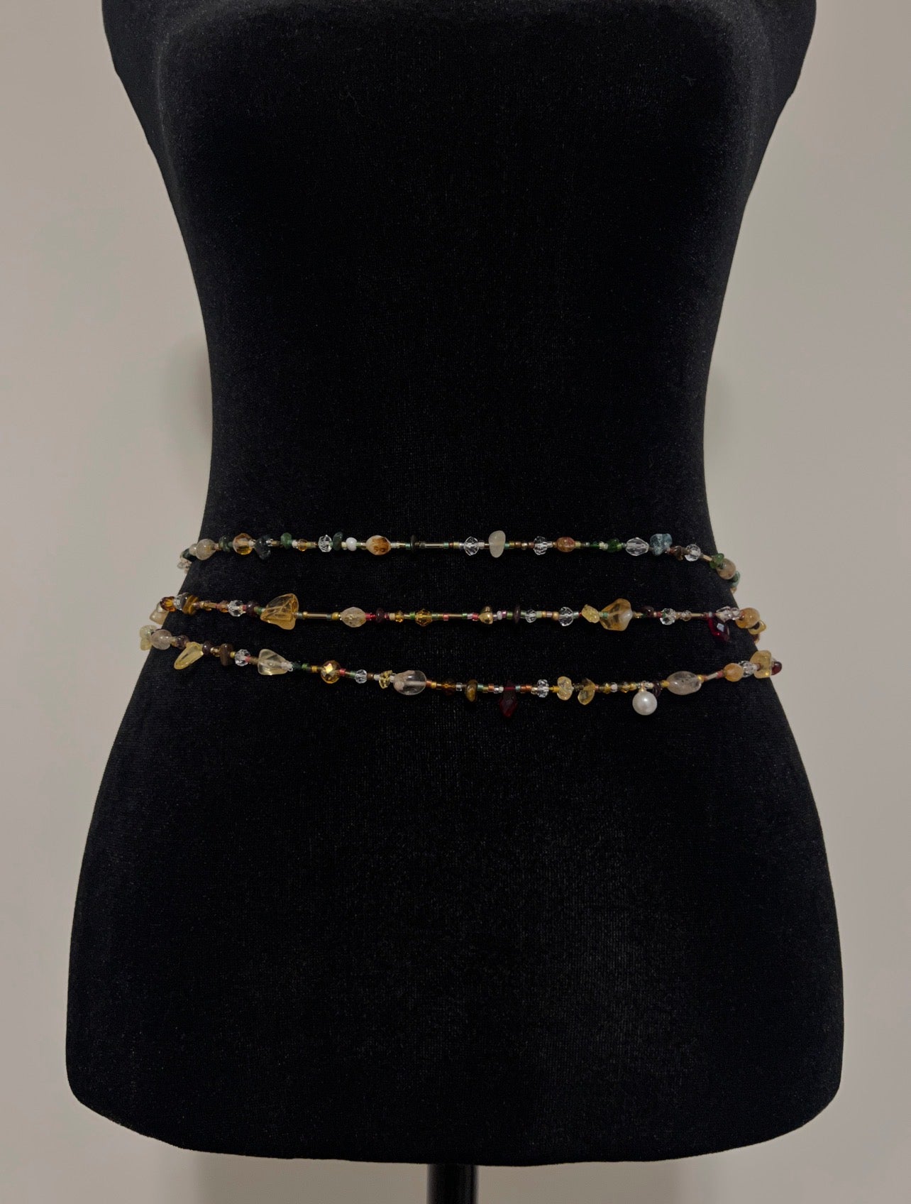 Handmade beaded waist chain with colorful gemstones and pearls displayed on black mannequin
