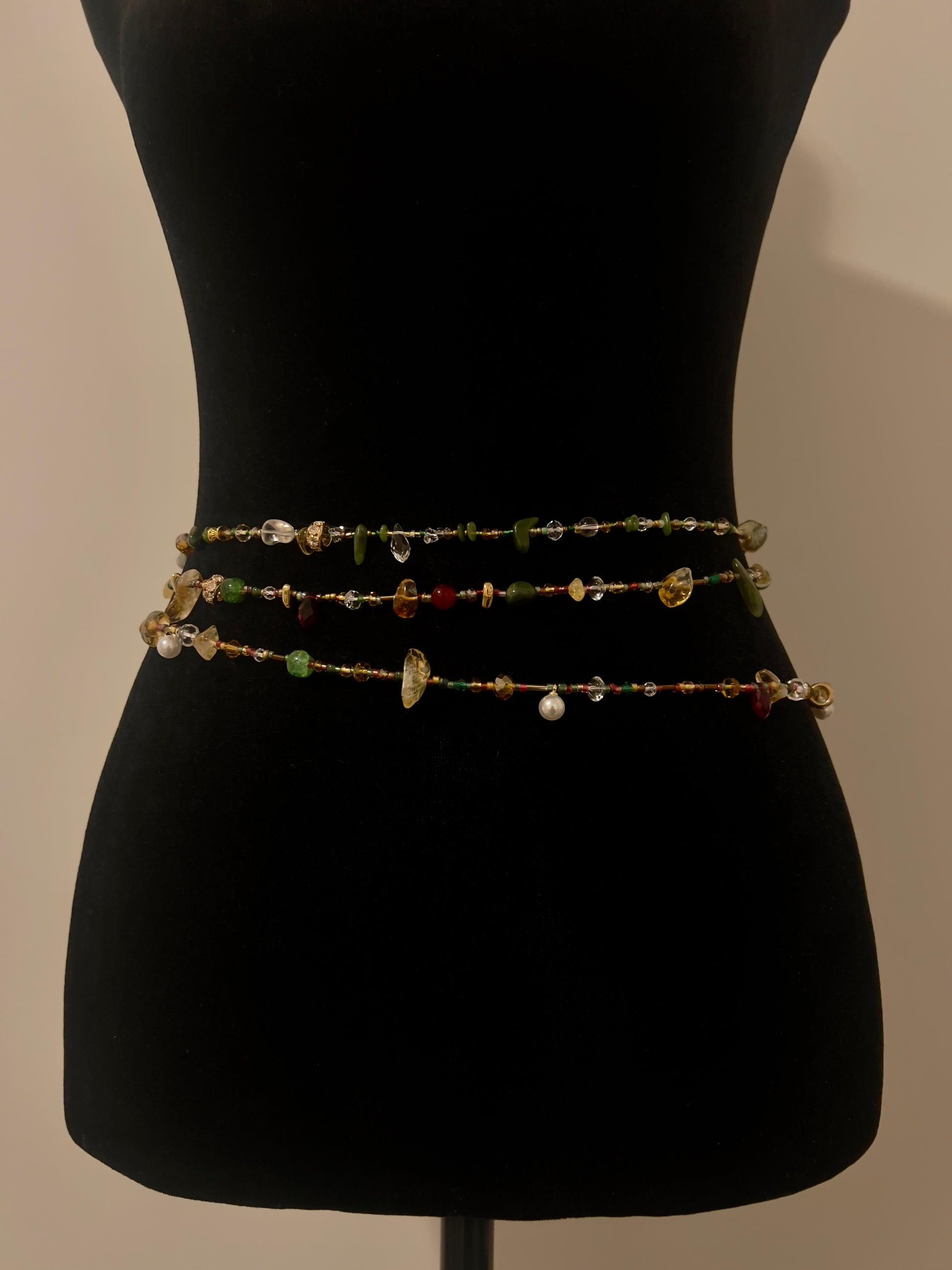 Handmade multi-layer beaded waist chain with green, amber, red, and clear gemstones on black mannequin